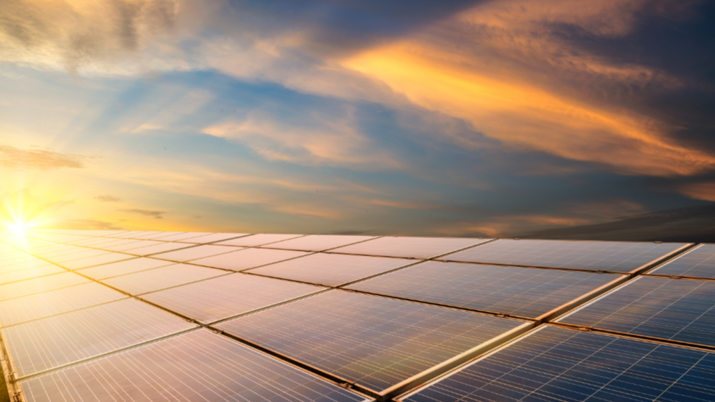 Solar panels with a scenic background of clouds and sun.